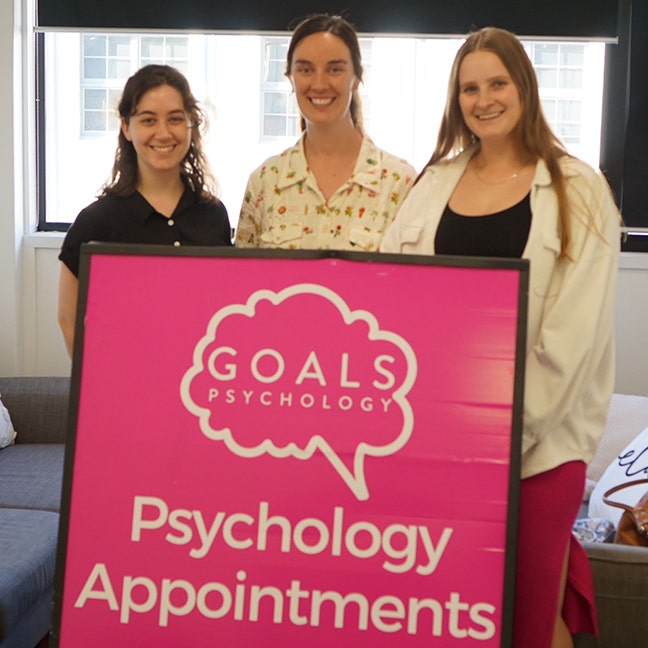 Goals Psychology team member standing behind their company sign