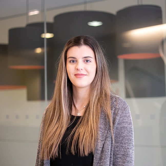 Emily wearing a grey jacket and smiling